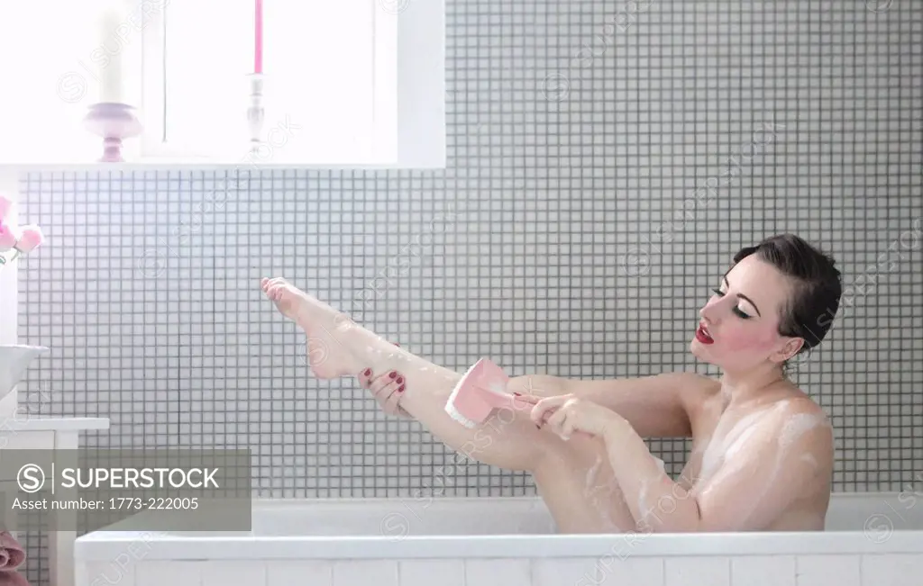 Young woman in bath, washing leg