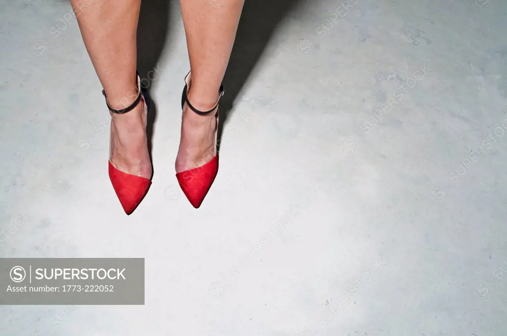 Close up of female legs and feet wearing red high heels