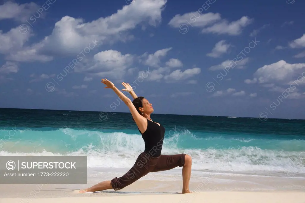 Mature woman in warrior pose on beach, Paradise Island, Nassau, Bahamas