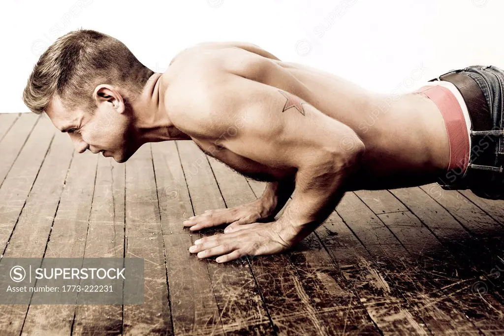 Mid adult man doing push ups on wooden floor