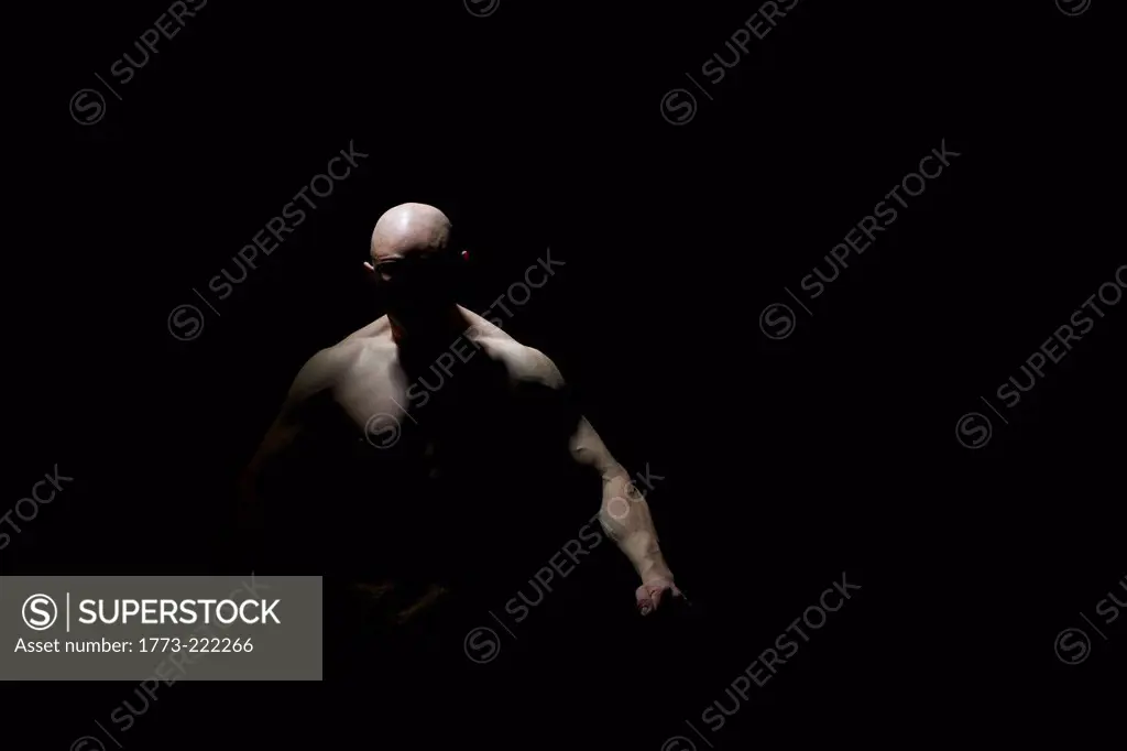 Studio portrait of aggressive bare chested man in shadow