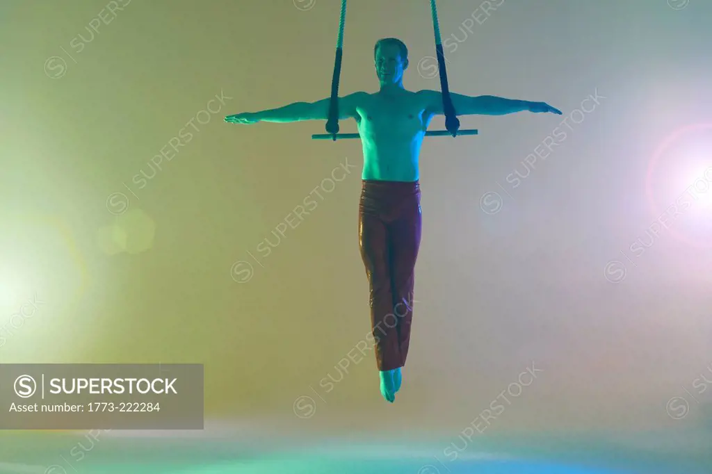 Trapeze artist on trapeze with arms out