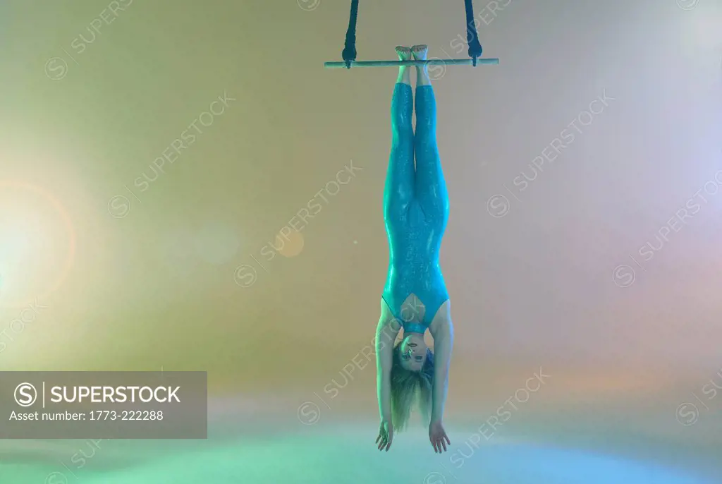 Trapeze artist hanging upside down on trapeze