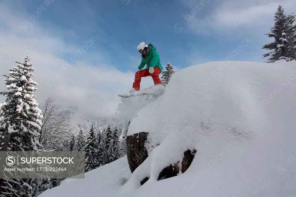 Snowboarder jumping down mountain