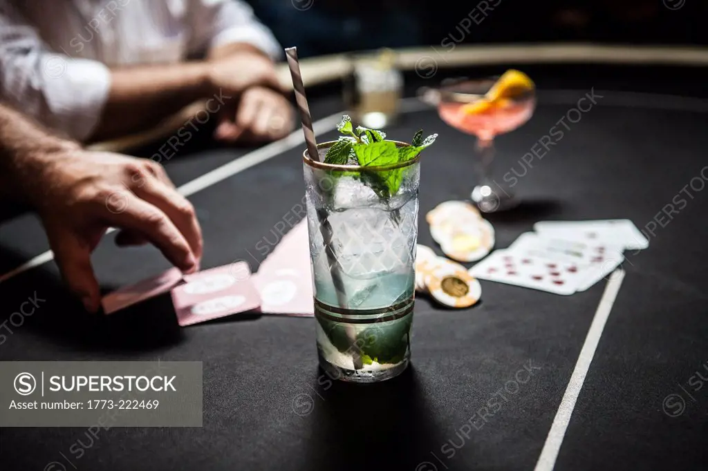 Cropped image of gambling table with playing cards, chips and cocktails