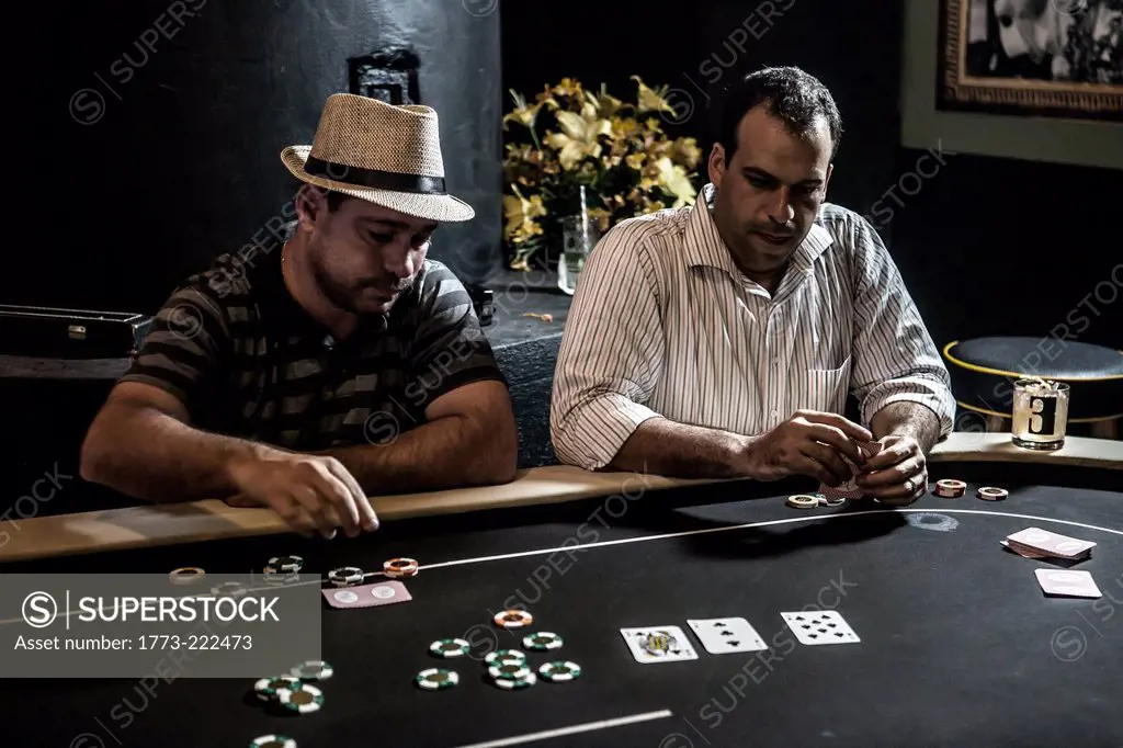 Mid adult men playing poker and drinking cocktails