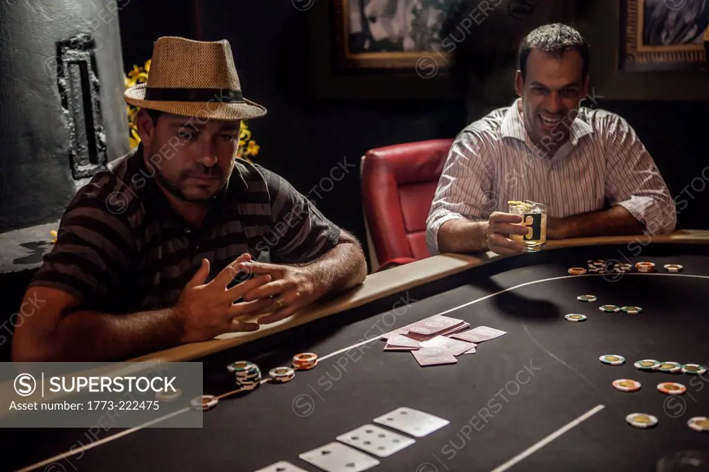 Mid adult men playing poker and drinking cocktails