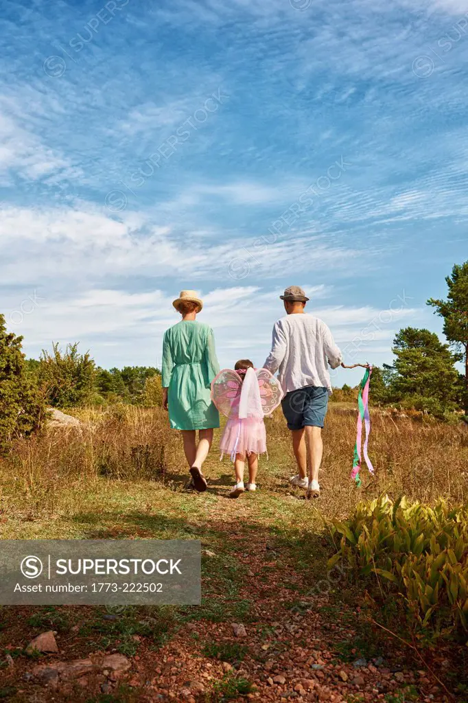 Family walking on grass, rear view, Eggergrund, Sweden