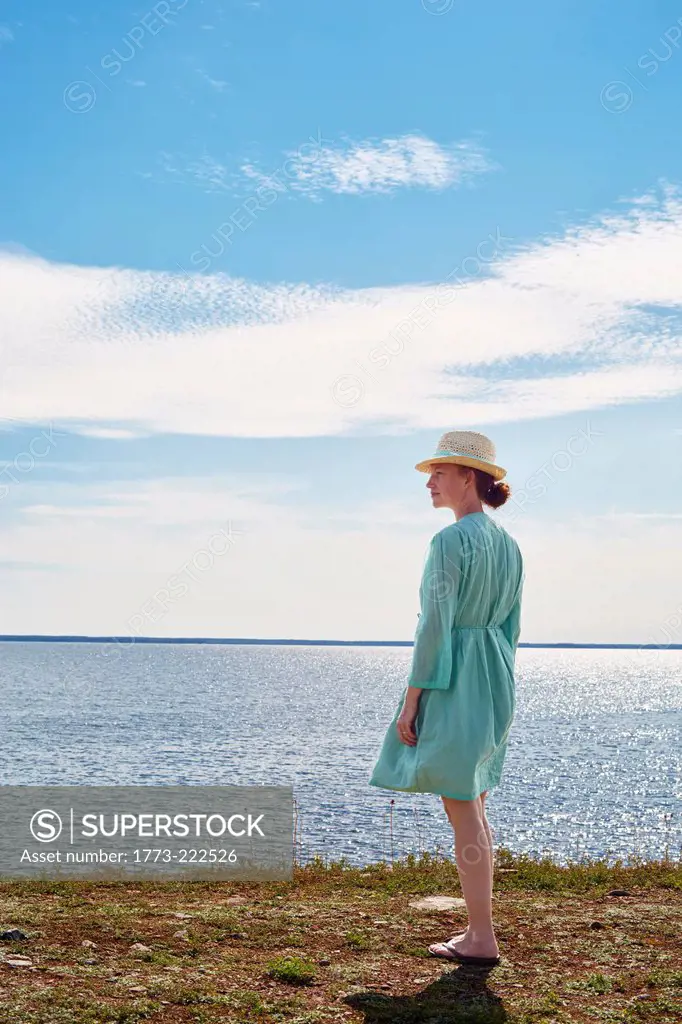 Mid adult woman standing by sea in green dress, Eggergrund, Sweden