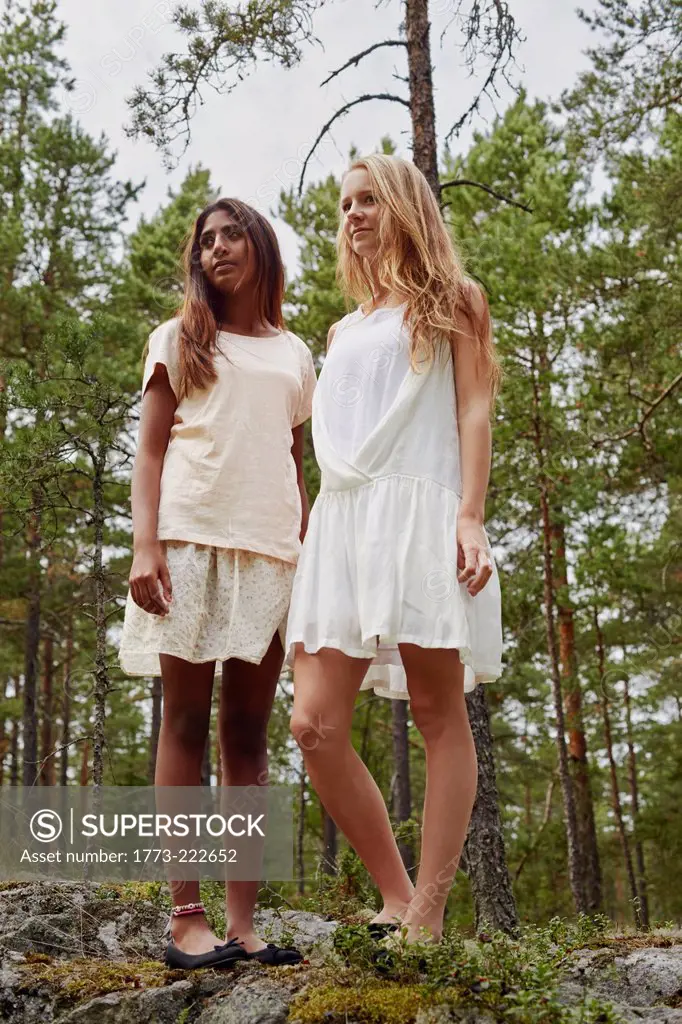 Portrait of teenage girls standing on rocks in forest
