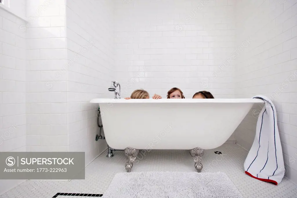 Three young girls peeking over bath