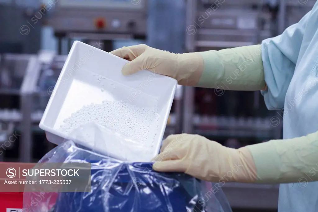 Laboratory technician emptying tablets into plastic bag