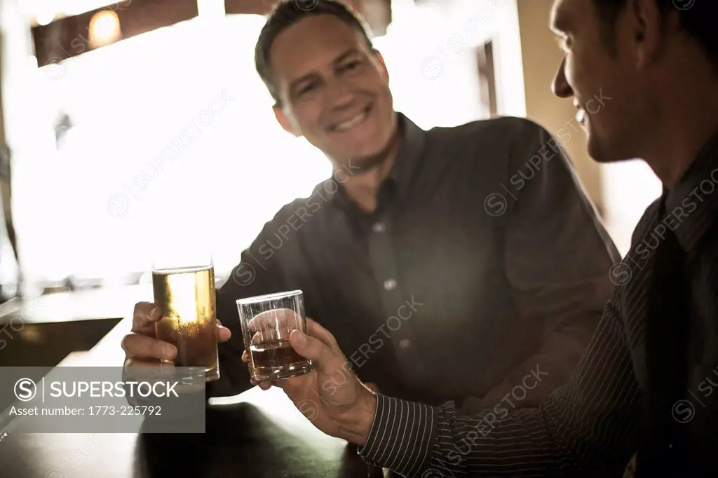 Two businessmen toasting drinks at the bar