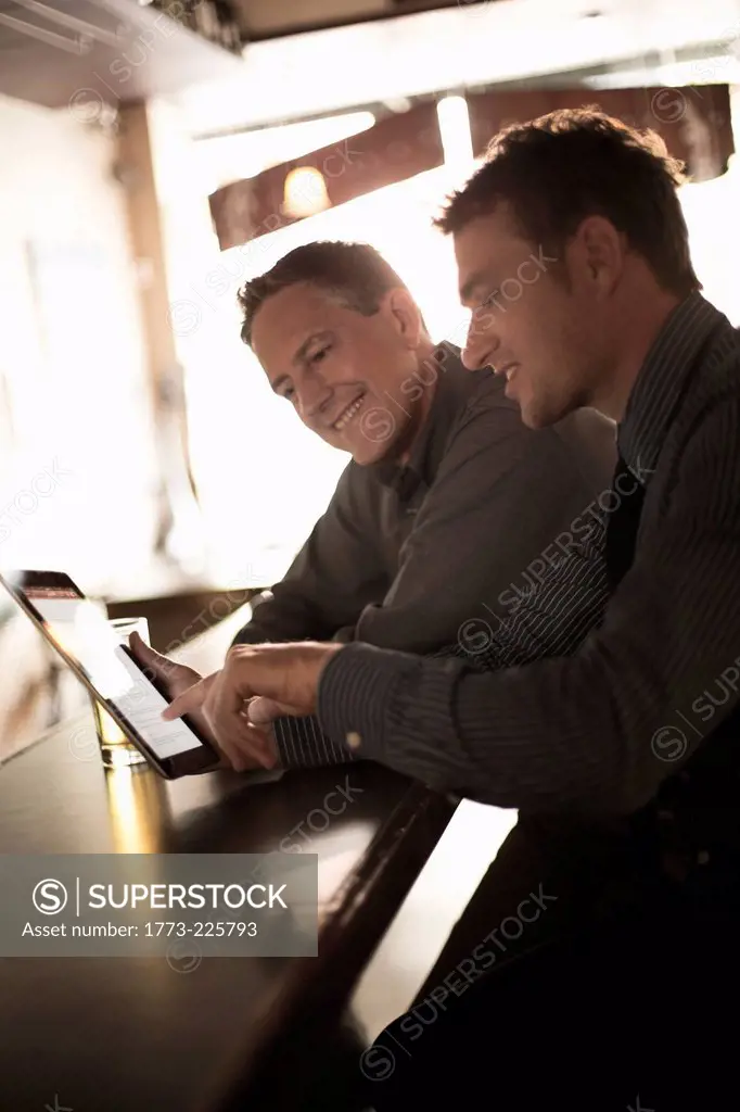 Two businessmen looking at digital at the bar
