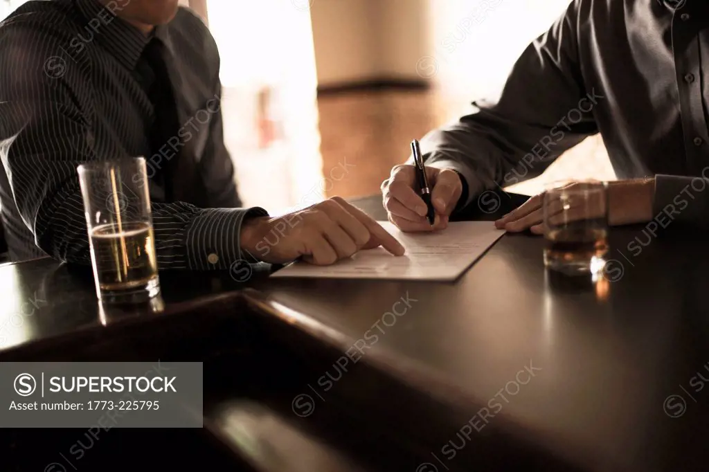 Partners signing business contract in a bar