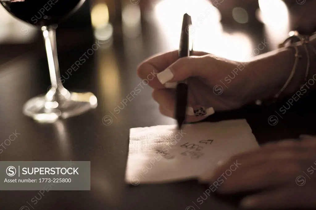 Close up of young woman writing her phone number on a napkin in bar