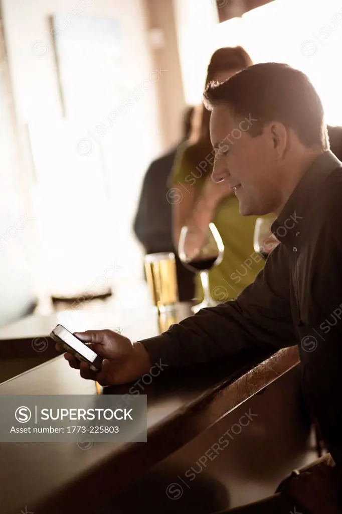 Businessman looking at cellphone in a wine bar