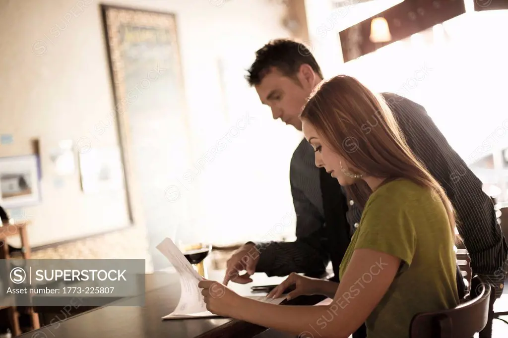 Business partners looking at paperwork in a wine bar