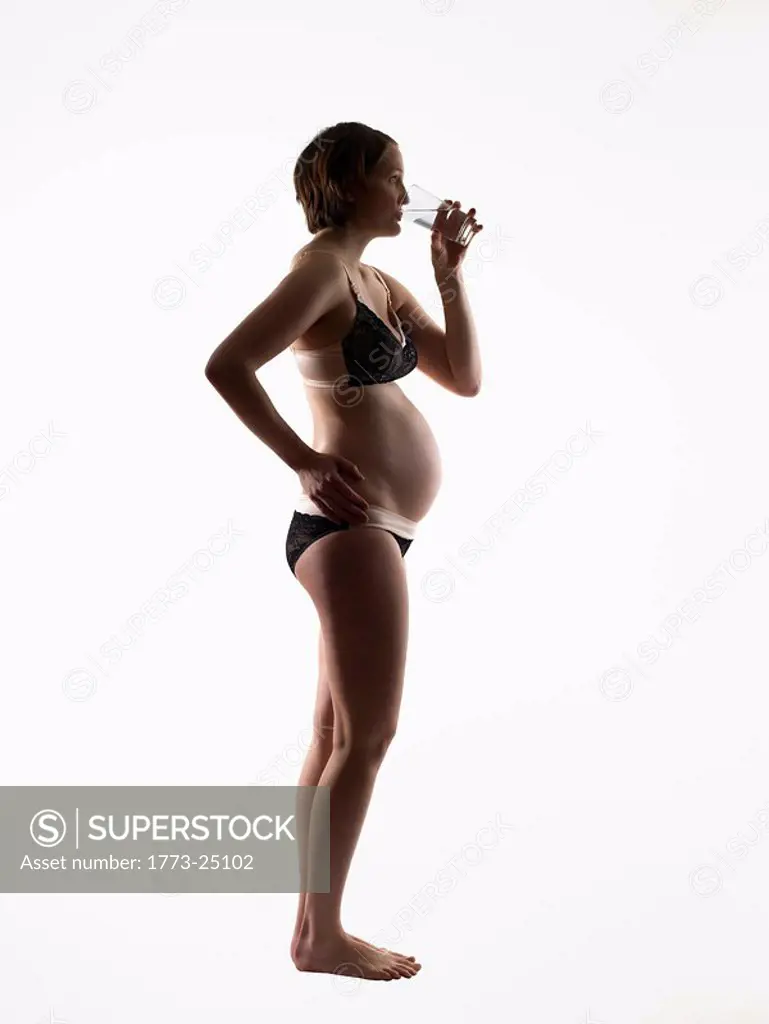 Silhouette of pregnant woman drinking water.