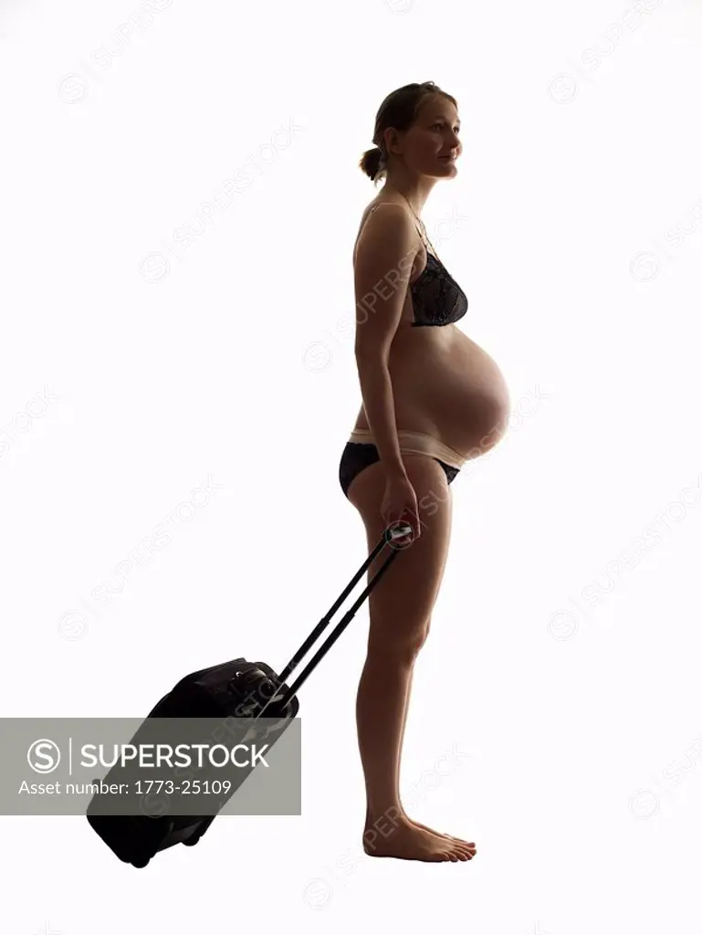 Silhouette of pregnant woman with over night case. Profile view.