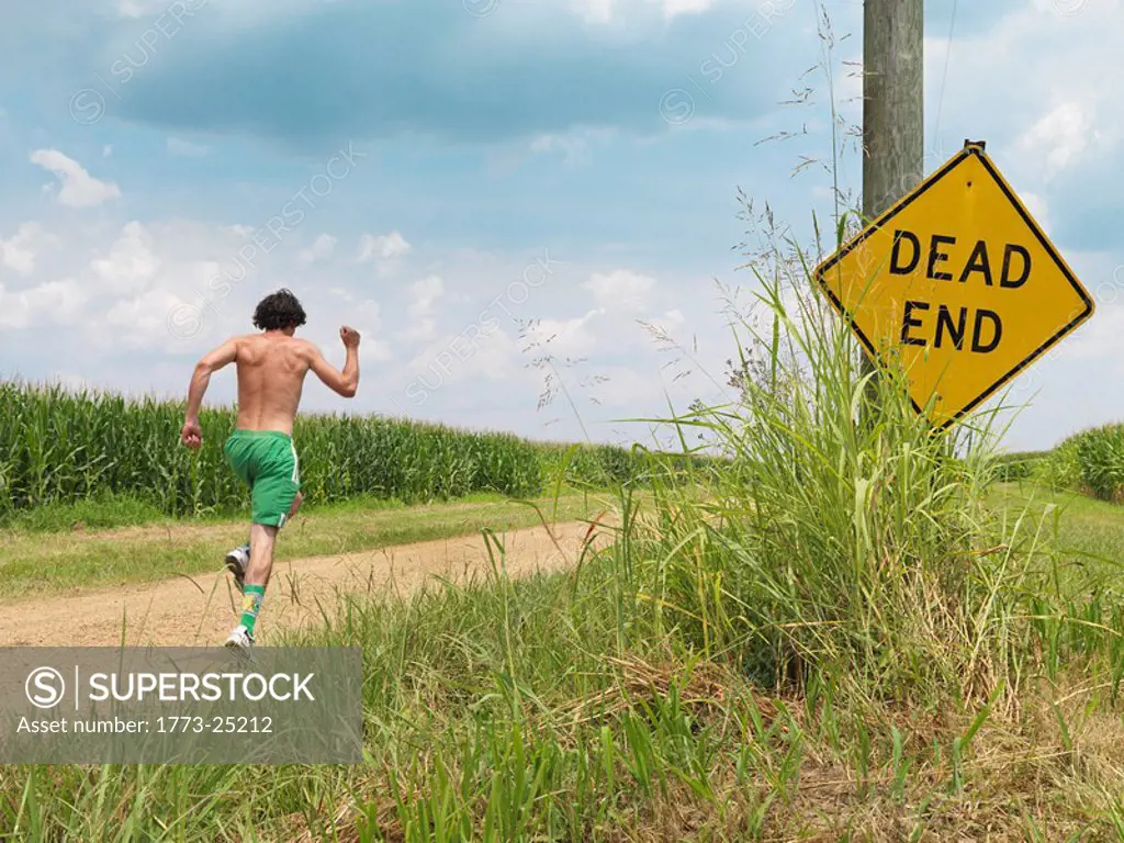 Man in shorts running past Dead End sign