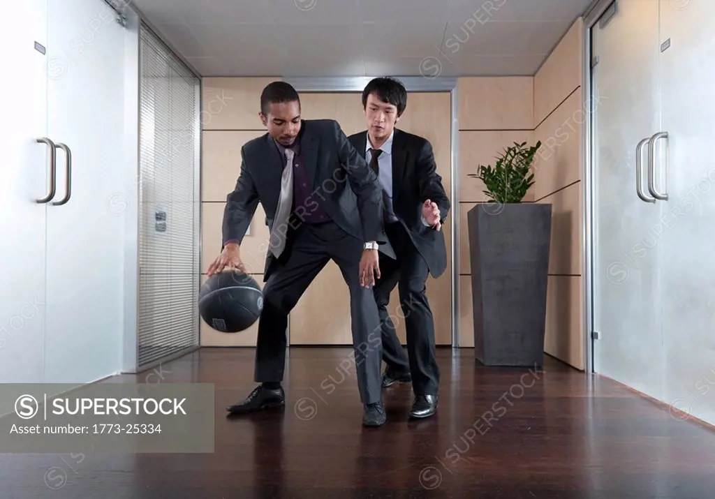Businessmen playing basketball in office