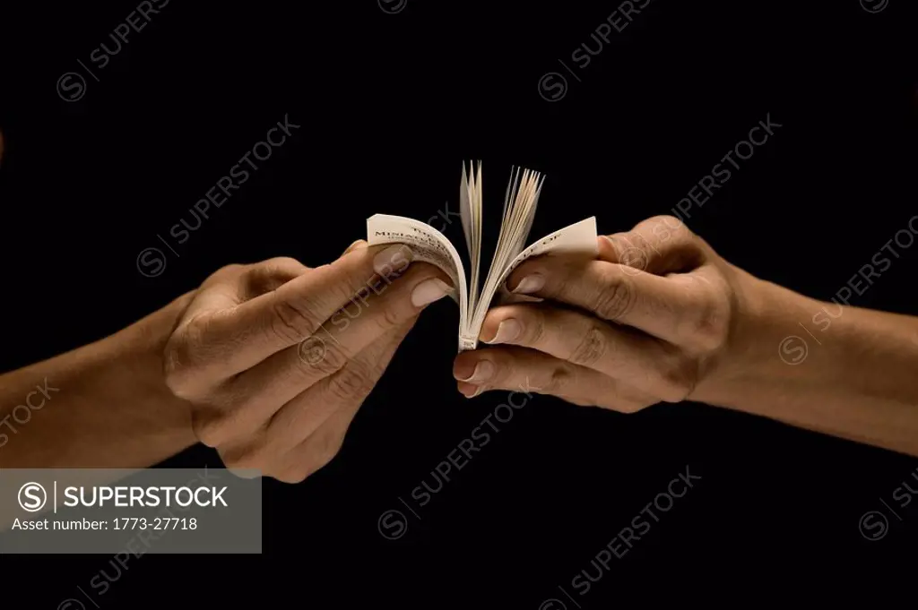 Hands reading tiny book