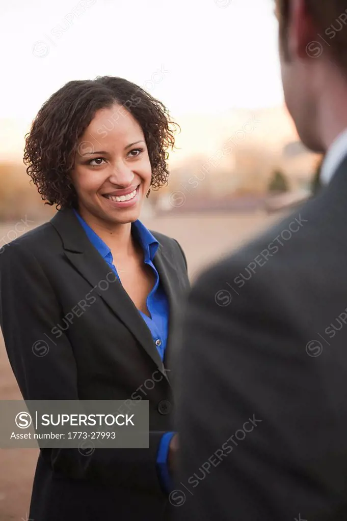 Woman in suit shaking hands with man