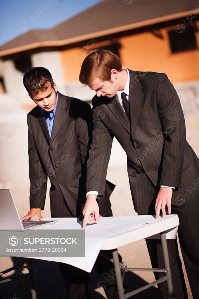 2 men examining plans on worksite