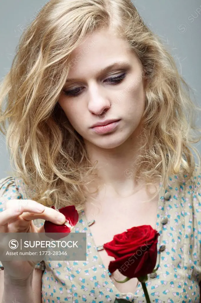 Woman pulling the petals off a rose