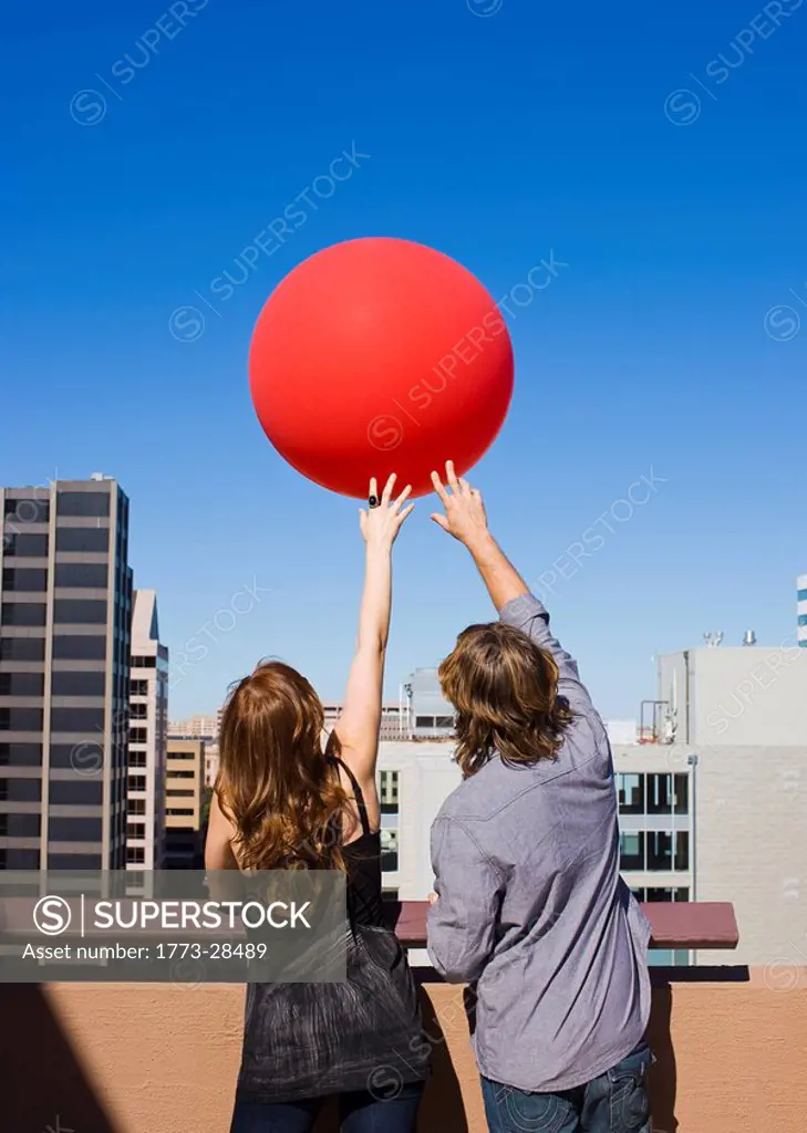 friends on roof top with red balloon