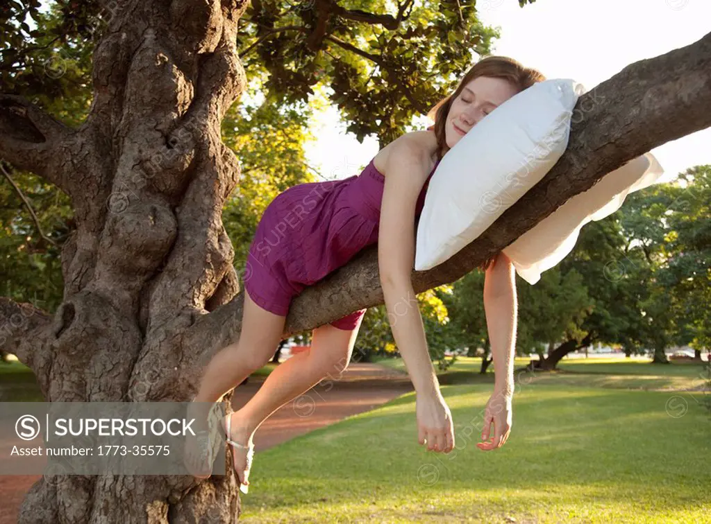 Young woman sleeping on a tree