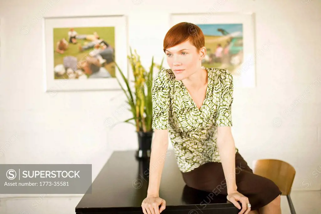 Small business owner sitting on desk in art gallery with framed contemporary photography on display