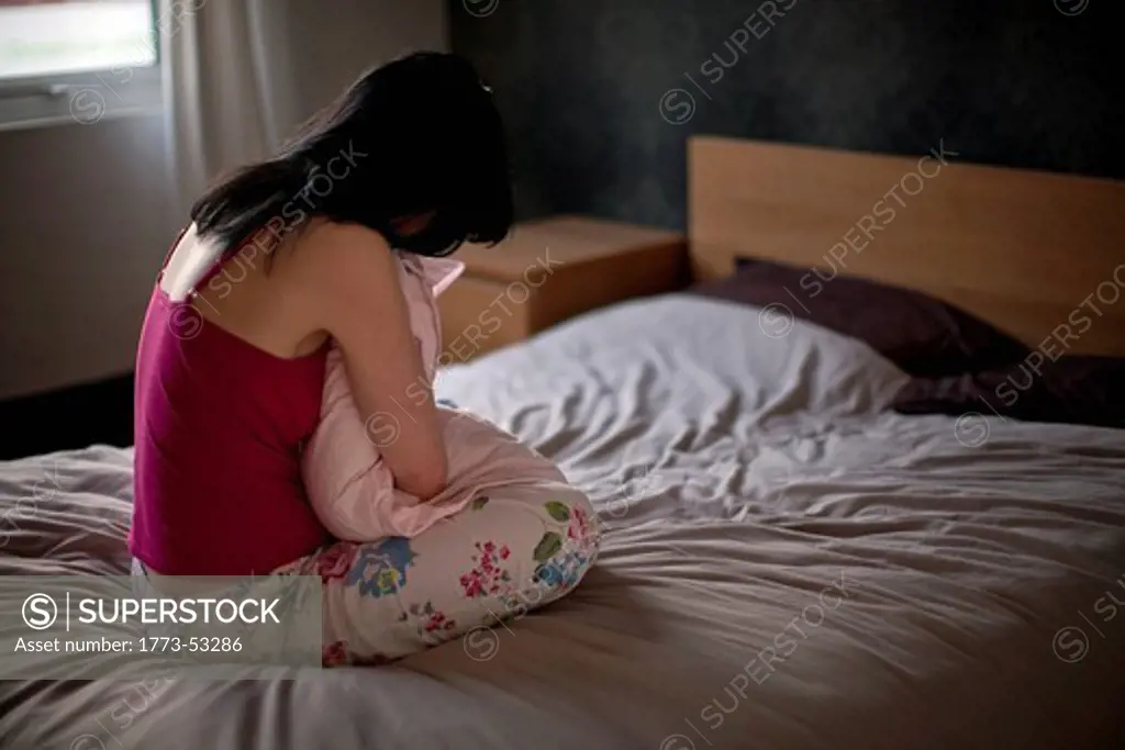 A young woman in bed, appearing depressed