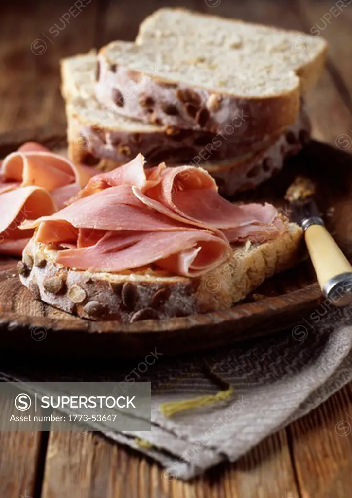 Hand carved Ham on slice of Rustic Seeded Bread on wooden rustic background