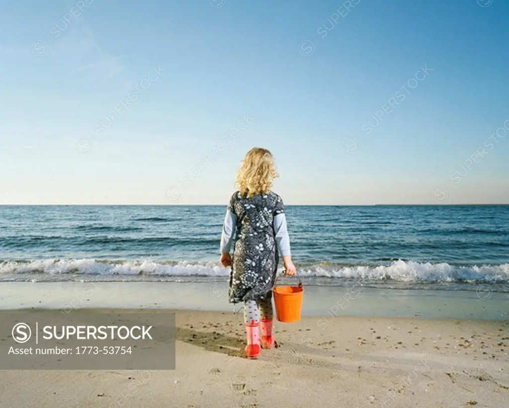 Girl walking in rainboots on beach