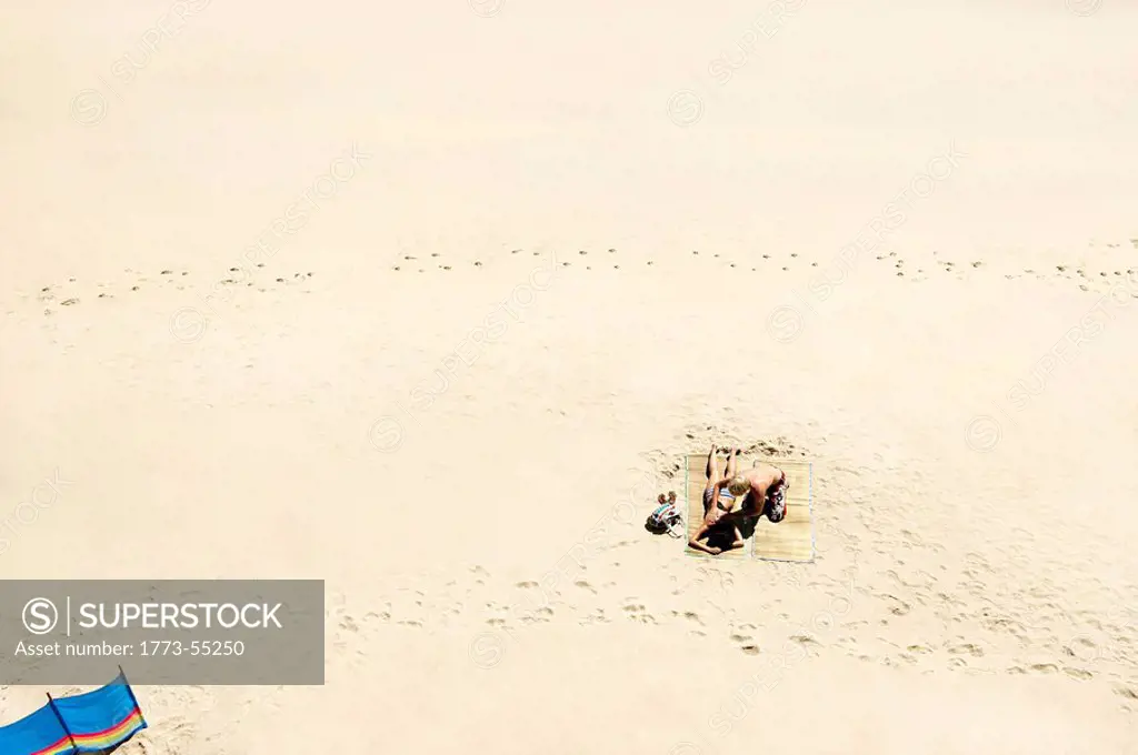 Couple sunbathing on white sandy beach