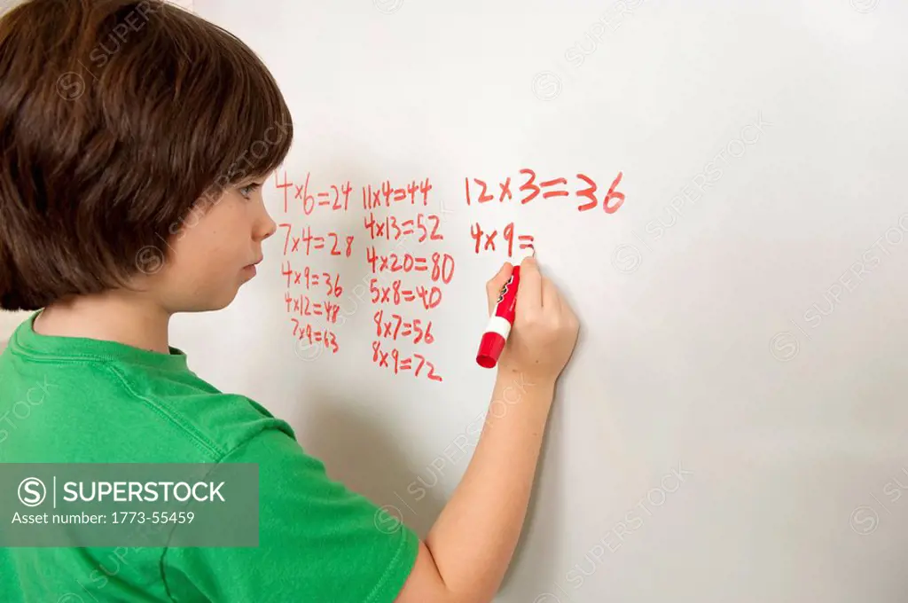 close up of hand of elementary school student working on math problem on white board