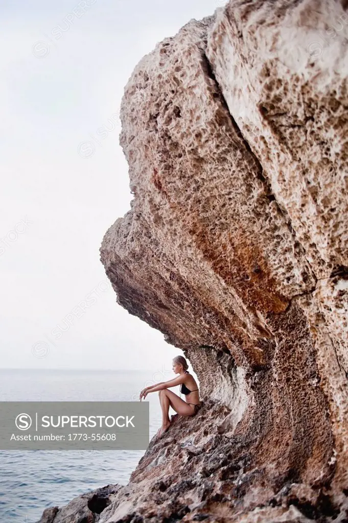 woman sitting on the rocks at cliffs