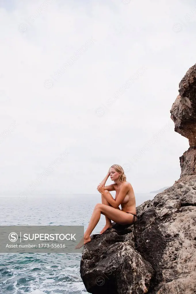 woman sitting on rocks at cliffs