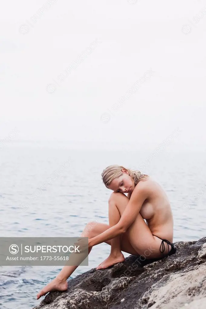 woman sitting on rocks at cliffs