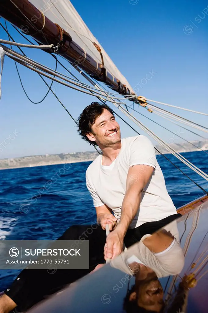 man smiling steering a sailing boat