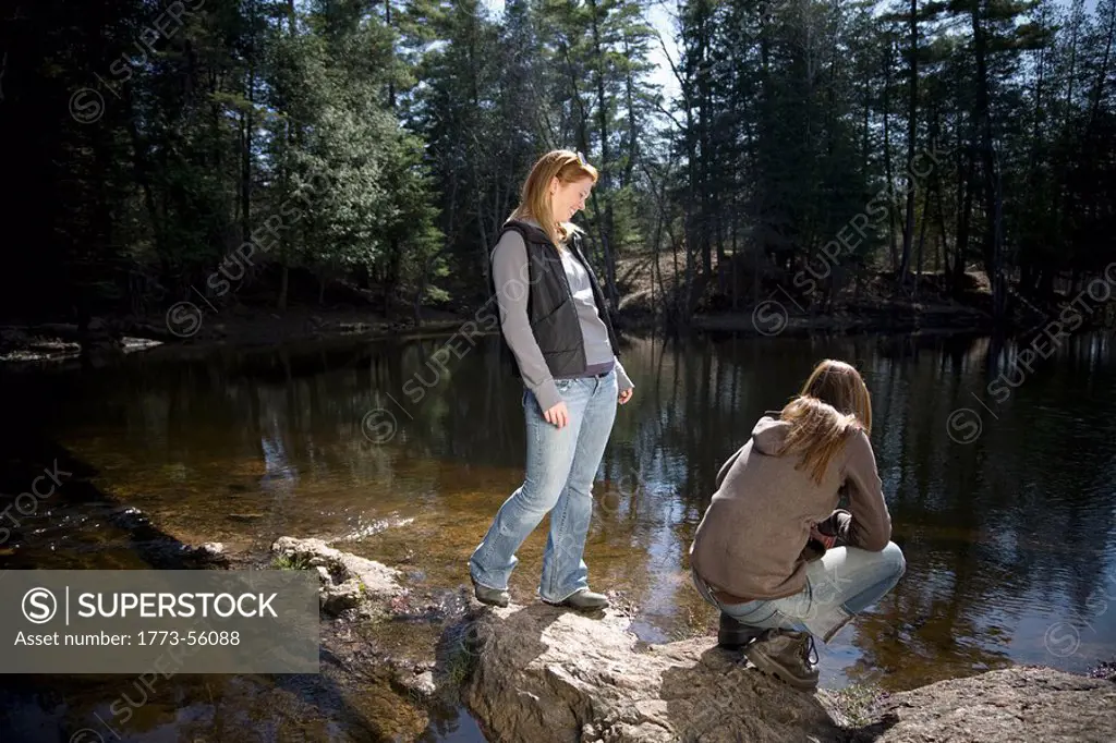 Two women standing beside lake