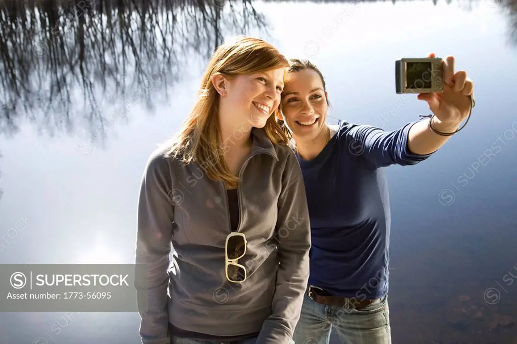 Two women with camera beside lake
