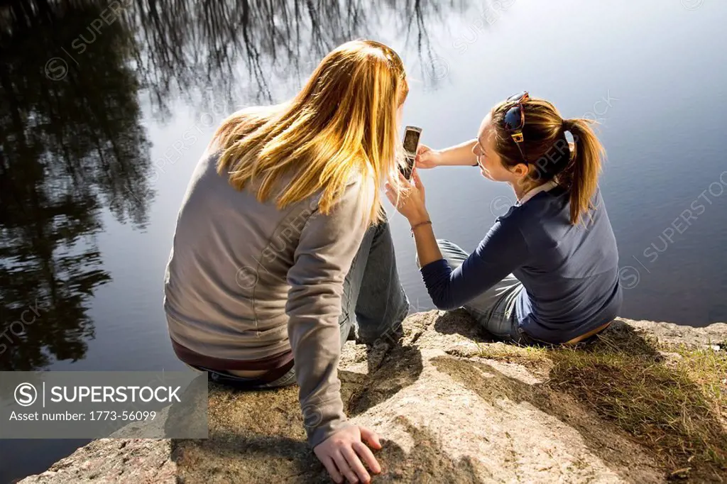 Two women looking at phone outdoors