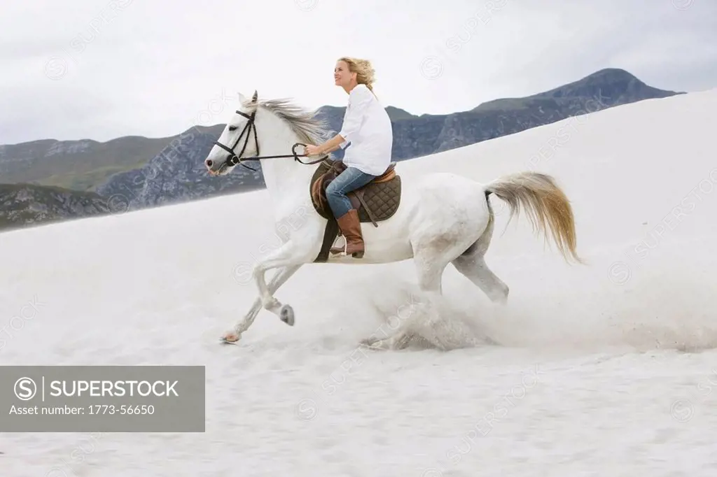 White horse with blond girl_rider,beach, mountains