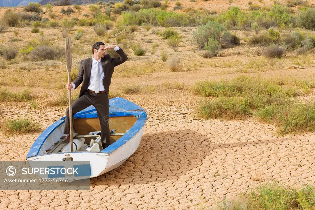 Businessman, rowing boat, dry desert