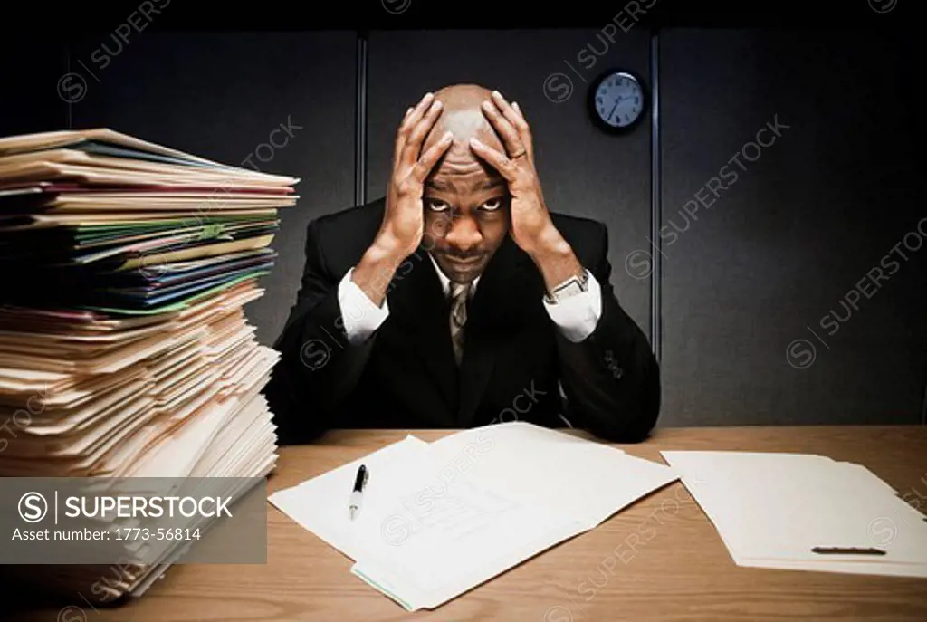 Businessman at desk with pile of folders
