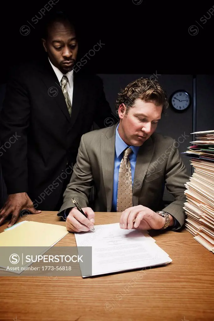 Man at desk with man over shoulder