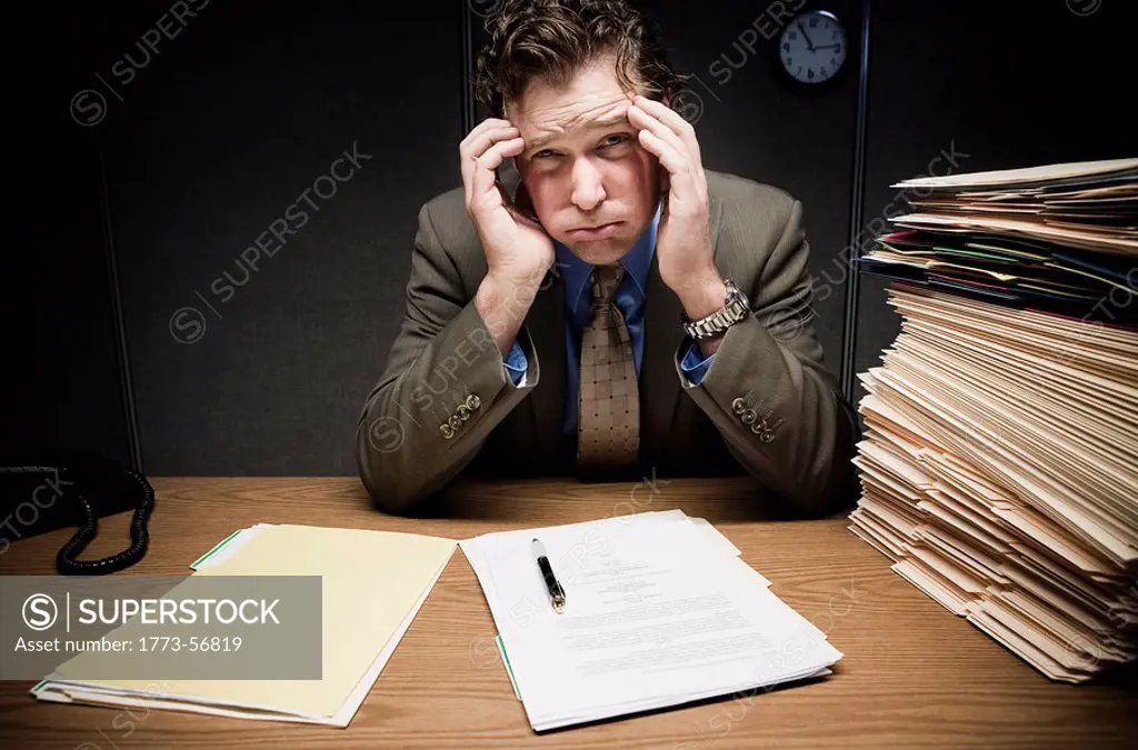 Stressed man at desk with paperwork
